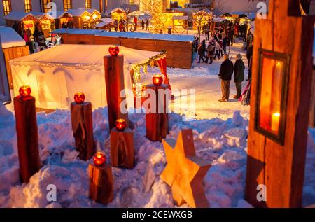 Ettal, Germania/Baviera – 31 dicembre 2019: Mercatino di Natale innevato con negozi illuminati in capanne di legno con regali e decorazioni fatte a mano. Foto Stock