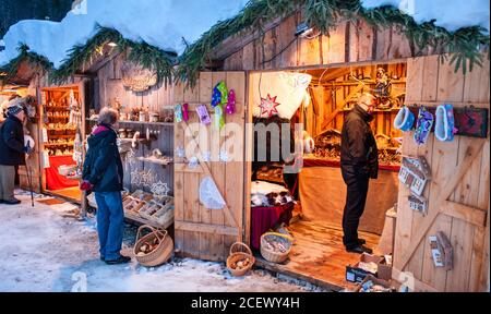 Ettal, Germania/Baviera – 31 dicembre 2019: Mercatino di Natale innevato con negozi illuminati in capanne di legno con regali e decorazioni fatte a mano. Foto Stock