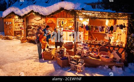 Ettal, Germania/Baviera – 31 dicembre 2019: Mercatino di Natale innevato con negozi illuminati in capanne di legno con regali e decorazioni fatte a mano. Foto Stock