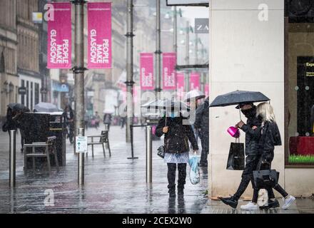 Membri del pubblico catturati in forte pioggia nel centro di Glasgow. Foto Stock