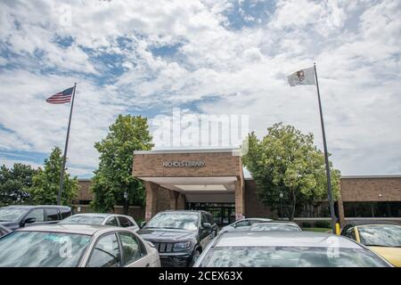 Naperville, Illinois, Stati Uniti-Aprile 24,2014: Nichols Library edificio in mattoni con bandiere e parcheggio nel centro di Naperville Foto Stock