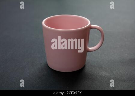 Tazza di caffè su sfondo nero. Mockup di bevande calde. Tazza vuota di colore rosa con maniglia pubblicizza, modello di branding Foto Stock