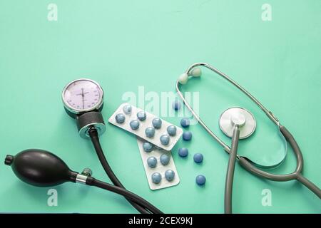 Misuratore di pressione sanguigna, stetoscopio medico e medicina su sfondo di colore blu pastello, vista ravvicinata. Trattamento ipertensione, farmaco concep Foto Stock