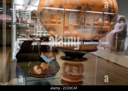 Ora riaperto dopo mesi di chiusura durante la pandemia di Coronavirus, un visitatore del British Museum che indossa una faccia coperta legge le descrizioni di un antico vaso greco che raffigura il matrimonio di Peleus e Tetis con animali immaginari (Atene, c580BC) dal pittore, Sophilos, il 2 settembre 2020, a Londra, Inghilterra. Alcuni dei primi visitatori che hanno prenotato in anticipo i biglietti gratuiti, ancora una volta godranno i manufatti storici di questa attrazione poluare di Londra. Foto Stock