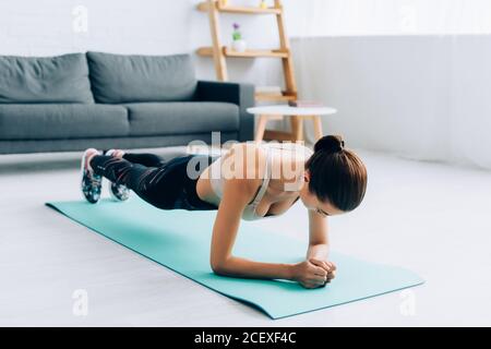 Fuoco selettivo di sportswoman che fa la pancia sul tappeto di idoneità a. casa Foto Stock