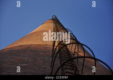 Industriale vecchio camino in mattoni senza fumo e cielo blu, scale che leeds alla cima, Rijeka, Croatia.isolato vecchio invecchiato alto fattore industriale. Foto Stock