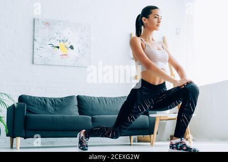 Fit sportivo che fa affondo durante l'allenamento a casa Foto Stock