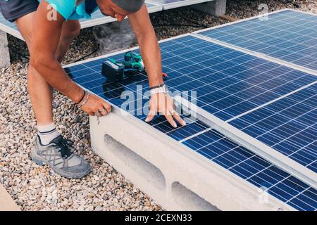 anonimo maschio ingegnere utilizzando un cacciavite elettrico e l'installazione solare contemporaneo batteria in fabbrica Foto Stock