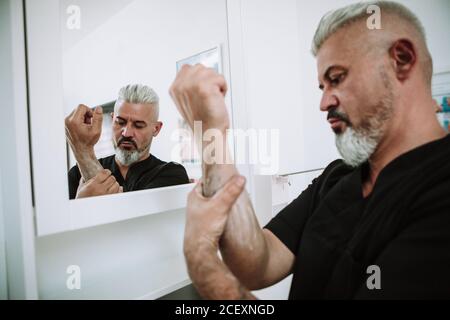 uomo in piedi in bagno e lavarsi le mani con acqua e sapone Foto Stock