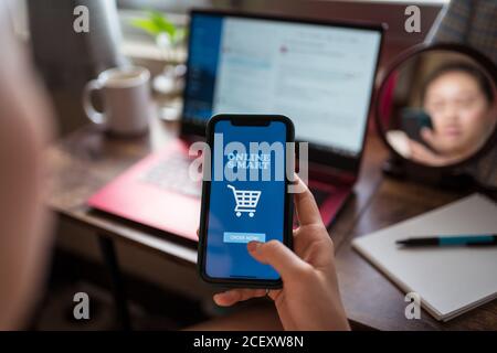 irriconoscibile femmina offuscata seduta al tavolo a casa e utilizzando applicazione moderna per lo shopping online mentre si sceglie il cibo per la produzione ordine Foto Stock
