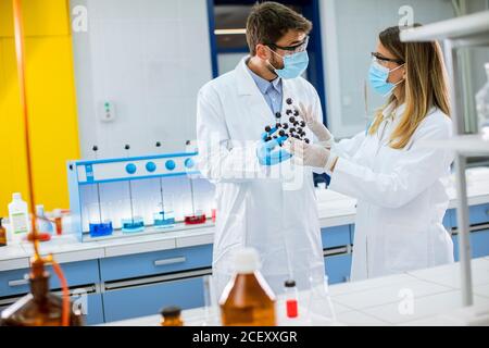 I giovani chimici con occhiali di protezione contengono il modello molecolare in laboratorio Foto Stock