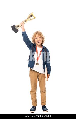 scolaro curly con medaglia d'oro che tiene trofeo e libro isolato su bianco Foto Stock