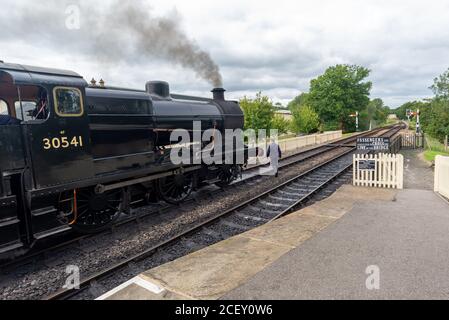 Operaio ferroviario sulla pista accanto al Rocket, locomotiva a vapore nero sulla linea ferroviaria Bluebell Heritage, Sheffield Park, East Sussex, Inghilterra, Regno Unito Foto Stock