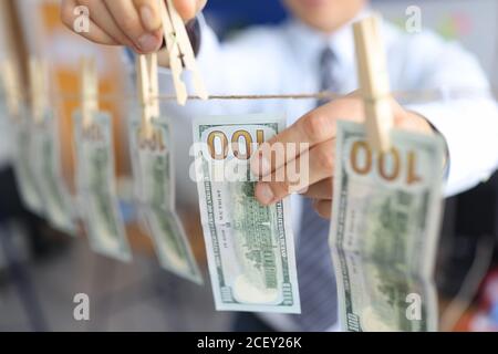 La mano dell'uomo appende le fatture di cento dollari sulla clothespin. Foto Stock