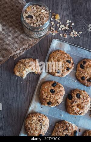 Yummy croccanti biscotti di farinata d'avena appena sfornati su carta da forno messo a tavola durante la colazione Foto Stock
