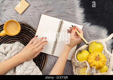 Le mani delle donne scrivono nell'acquisto del notepad per fare la lista Foto Stock