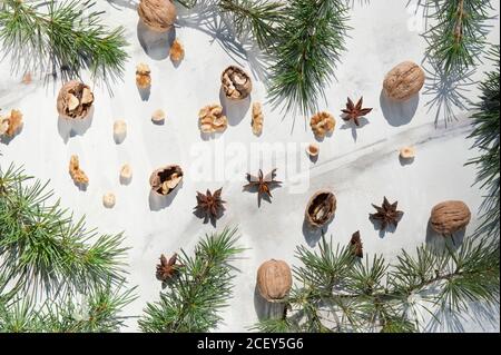 Decorazione xmas con rami di abete verde naturale composti da noci e stelle aromatiche di anice su superficie di marmo bianco Foto Stock