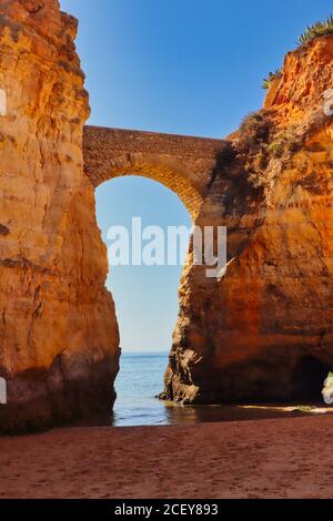 Un arco tra due rocce dorate a Praia dos Estudiantes a Lagos, Portogallo Foto Stock