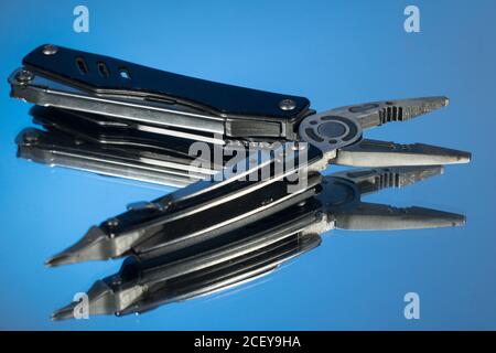 Coltello da caccia e multitool su sfondo scuro. Custodie in pelle marrone vicino al coltello e al multitool. Foto Stock