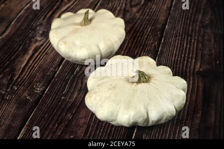 Due zucche di pattypan bianche su tavola di legno scuro Foto Stock