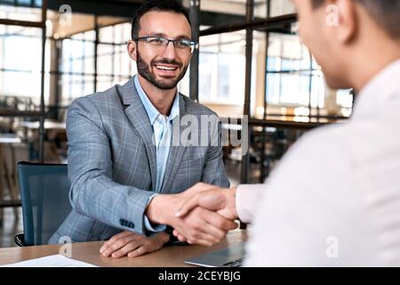 Concetto di reclutamento. Manager e candidato di lavoro seduta in ufficio scuotendo le mani riuscito assumere allegro Foto Stock