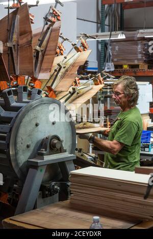 Un operaio adduce i pezzi di legno esotico abbinati per le spalle di chitarra insieme su una speciale macchina di bloccaggio nella fabbrica di chitarra Taylor a El Cajon, Cal Foto Stock