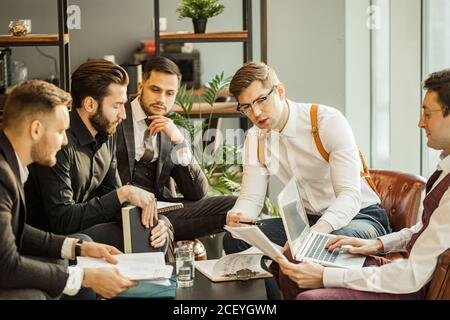 giovani uomini d'affari caucasici di successo si riuniscono per rendere utile la cooperazione tra le imprese, sviluppando insieme strategie di business in offic Foto Stock