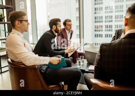 giovani uomini d'affari caucasici di successo si riuniscono per rendere utile la cooperazione tra le imprese, sviluppando insieme strategie di business in offic Foto Stock