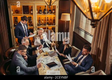 deliziosa capogruppo femminile in suite bianca e blusa nera con diversi supplementi, sorridendo in generale, portando felice incontro a una cunclusione, t Foto Stock