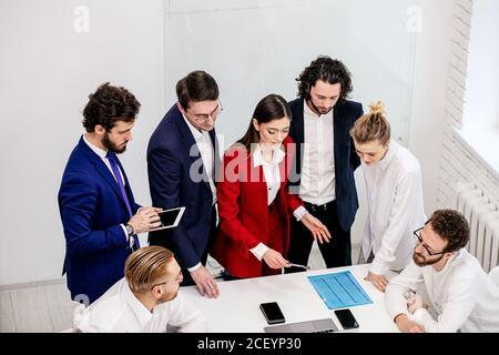 riunione di lavoro di un team di successo amichevole in sala riunioni, leader attivi ed entusiasti che hanno buoni risultati sul lavoro. isolato in business off leggero Foto Stock