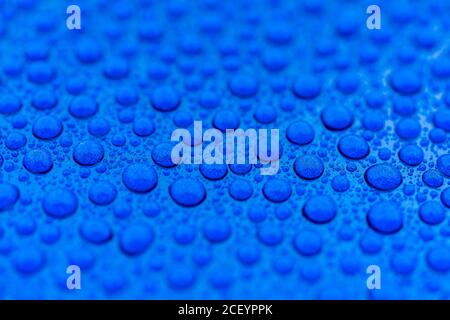 Primo piano di gocce d'acqua sul cappuccio di un blu auto dopo rivestimento ceramico Foto Stock