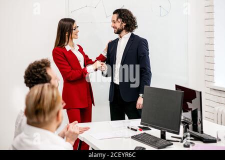 giovane capo femmina e miglior operaio del mese stare insieme, boss scuotendo la mano all'uomo per il suo buon lavoro Foto Stock