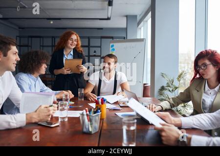 Un giovane team caucasico di partner commerciali che cooperano in ufficio insieme, si è riunito per discutere. Concetto di occupazione professionale Foto Stock