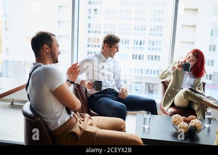 Dirigenti che hanno una discussione amichevole durante la pausa, le idee di affari, la costruzione della strategia di affari mentre si siitng sul tavolo insieme. Background di ufficio Foto Stock