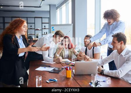 I giovani collaboratori caucasici hanno scioccato dopo il successo finale del loro affare, sorpresi e felici uomini d'affari in carica Foto Stock