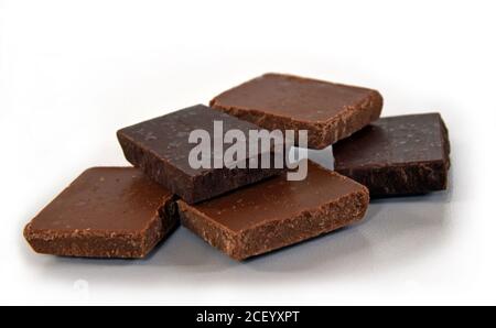 Cubetti di latte e cioccolato fondente. Pila di cioccolato su sfondo bianco. Pila di cioccolato. Piccoli pezzi di cioccolato fondente. Foto Stock