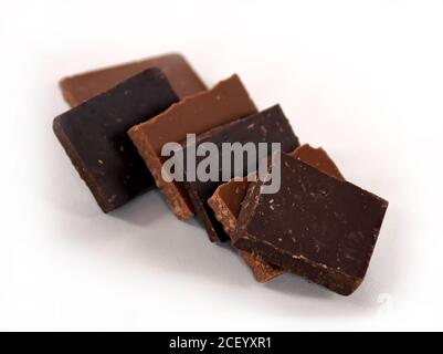 Cubetti di latte e cioccolato fondente. Pila di cioccolato su sfondo bianco. Pila di cioccolato. Piccoli pezzi di cioccolato fondente. Foto Stock