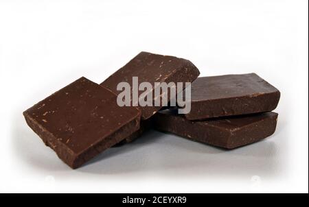 Cubetti di latte e cioccolato fondente. Pila di cioccolato su sfondo bianco. Pila di cioccolato. Piccoli pezzi di cioccolato fondente. Foto Stock