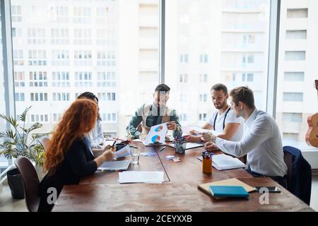 Dirigenti che hanno una discussione amichevole durante la pausa, le idee di affari, la costruzione della strategia di affari mentre si siitng sul tavolo insieme. Background di ufficio Foto Stock