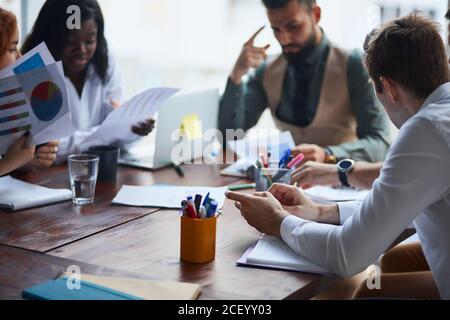 Dirigenti che hanno una discussione amichevole durante la pausa, le idee di affari, la costruzione della strategia di affari mentre si siitng sul tavolo insieme. Background di ufficio Foto Stock