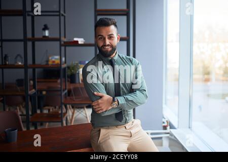 Giovane uomo simpatico dal medio Oriente, uomo d'affari in ufficio, telecamera, leader di squadra di successo con abbigliamento formale, pos Foto Stock