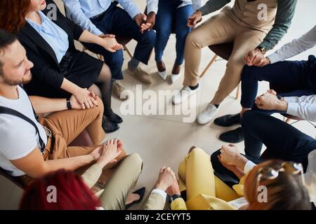 Molti colleghi si sono riuniti per pregare per il miglior lavoro in ufficio, il team aziendale di successo siede in cerchio Foto Stock