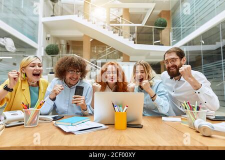 I grafici di successo sono molto contenti, gridano a voce alta, si accucchiano con piacere, esprimono felicità, soddisfatti di ricevere notizie impressionanti, vincere concetto Foto Stock