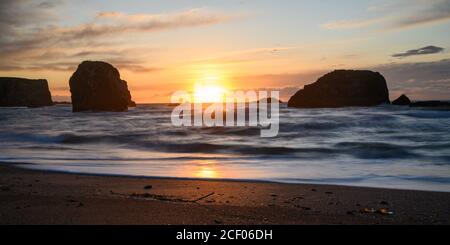 Tramonto tra rocce silhouette nell'oceano. Molto spazio per il testo. Foto Stock