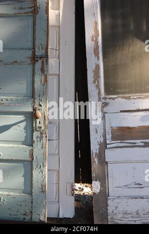 Decrepit vecchie porte in legno con vernice sbiadita, turchese peeling e bianca Foto Stock