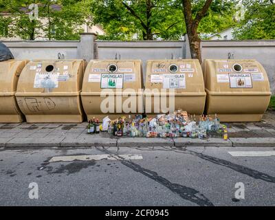 Bottiglie vuote davanti ai contenitori riempiti in eccesso in una città. Un simbolo delle reali questioni relative ai rifiuti nel mondo. Foto Stock