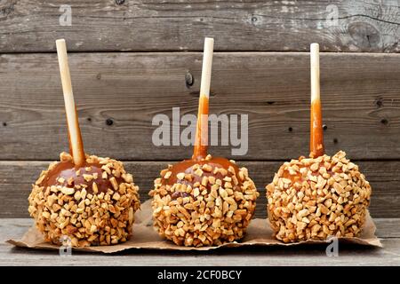 Tre mele natalizie al caramello con noci contro un legno rustico sfondo Foto Stock