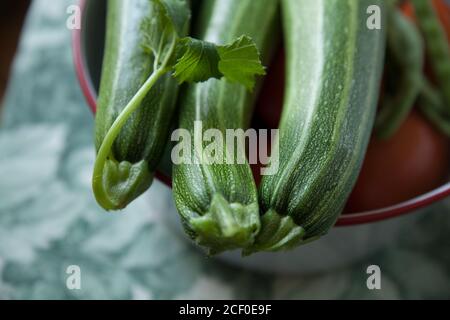 Tre zucchine coltivate in casa in una ciotola sul tavolo. Foto Stock