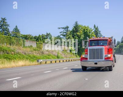 Potente carro Big RIG luminoso rosso classico diesel semi-camion con gli accessori cromati e gli avvisatori acustici sul tetto per il trasporto si abbassano semirimorchi in esecuzione sul th Foto Stock