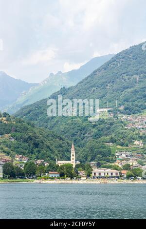 Paesaggio con la città di Domaso sul lago di Como. Alte montagne e colline con foresta. La Chiesa di San Bartolomeo. Foto Stock